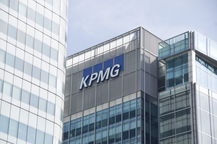 KPMG office building exterior with company logo under clear blue sky, representing global professional services firm