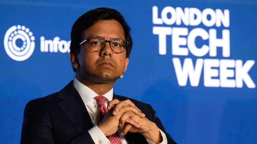 Kanishka Narayan, wearing glasses and a suit, speaks at London Tech Week, with the event logo visible.