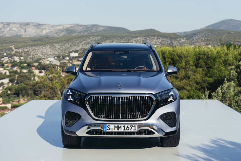 Front view of a silver Mercedes-Benz Maybach SUV with a prominent grille, parked outdoors with mountains in the background