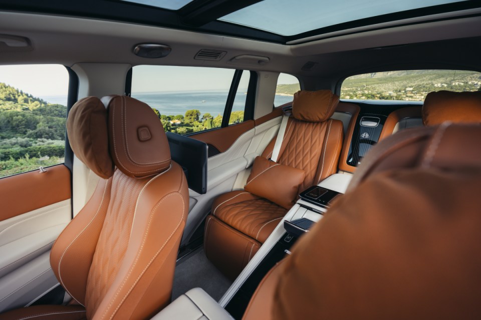 Luxurious Mercedes-Maybach interior with tan leather seats, rear entertainment screens, and panoramic sunroof overlooking ...