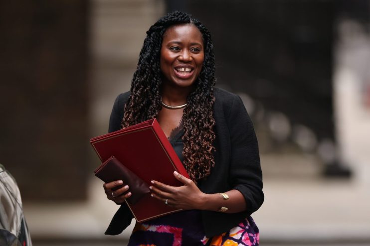 Miatta Fahnbulleh, director of New Economics Foundation, smiling and holding red documents, wearing a black blazer.