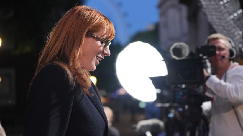 Angela Rayner, Deputy Leader of the Labour Party, smiling in glasses at an event with camera crew and lighting