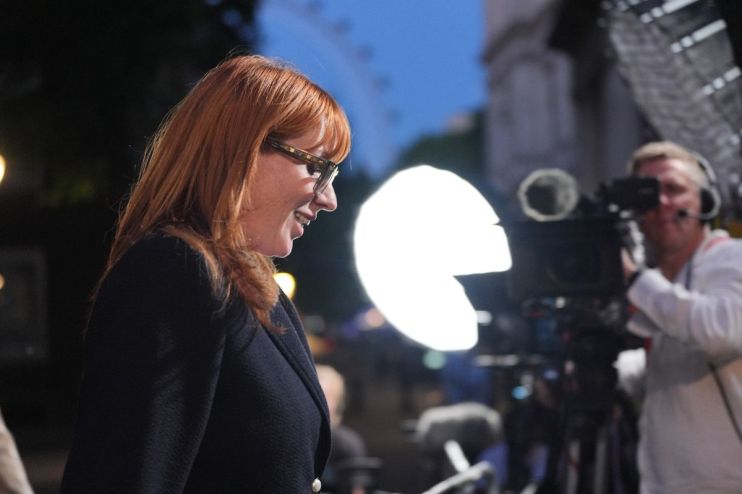 Angela Rayner, Deputy Leader of the Labour Party, smiling in glasses at an event with camera crew and lighting
