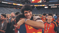 Carlos Alcaraz embracing a person, smiling, wearing a Rolex Daytona Rainbow watch at a stadium event