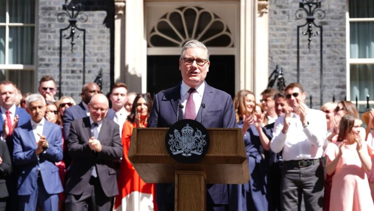Keir Starmer addressing the media at a press conference, wearing a navy suit, discussing recent political developments.
