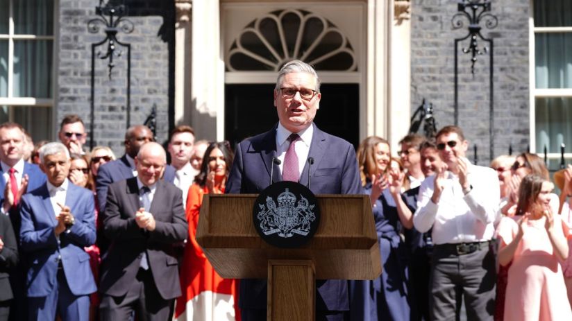Keir Starmer addressing the media at a press conference, wearing a navy suit, discussing recent political developments.