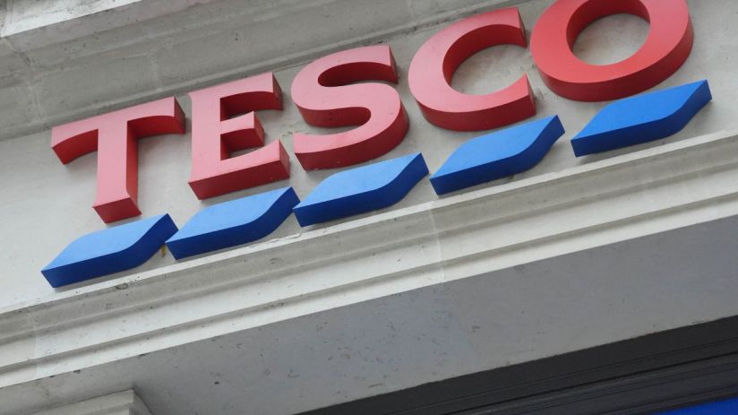 Tesco storefront with shoppers entering and exiting, highlighting the brands popularity and bustling retail environment