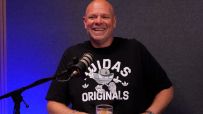 Celebrity chef Tom Kerridge smiling during a cooking demonstration, wearing a chefs uniform in a professional kitchen setting