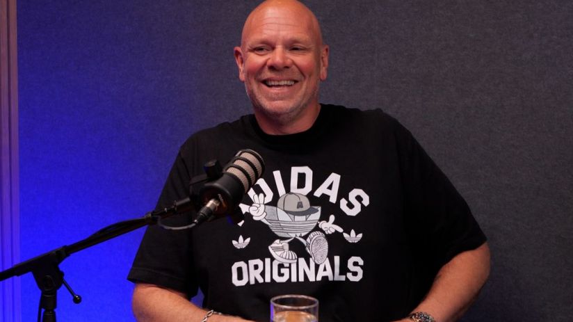 Celebrity chef Tom Kerridge smiling during a cooking demonstration, wearing a chefs uniform in a professional kitchen setting