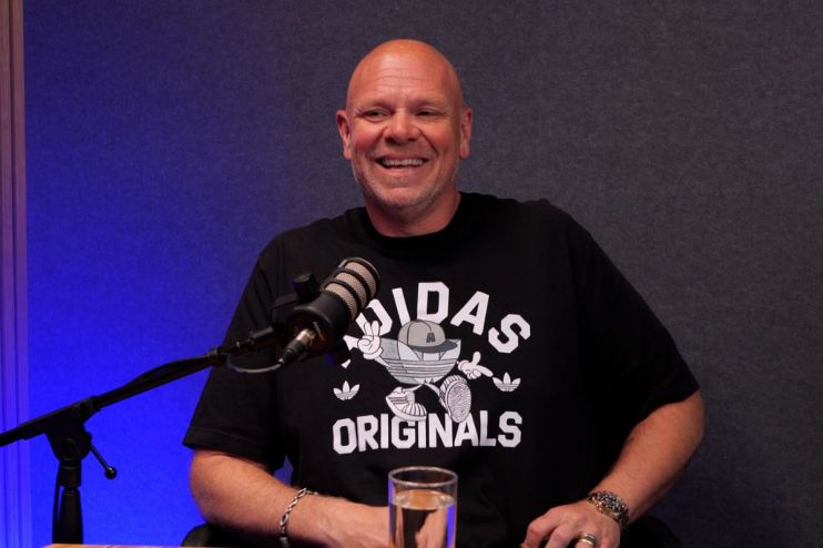 Celebrity chef Tom Kerridge smiling during a cooking demonstration, wearing a chefs uniform in a professional kitchen setting