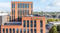 Unite Students building with brick facade and blue windows, city skyline in background under blue sky