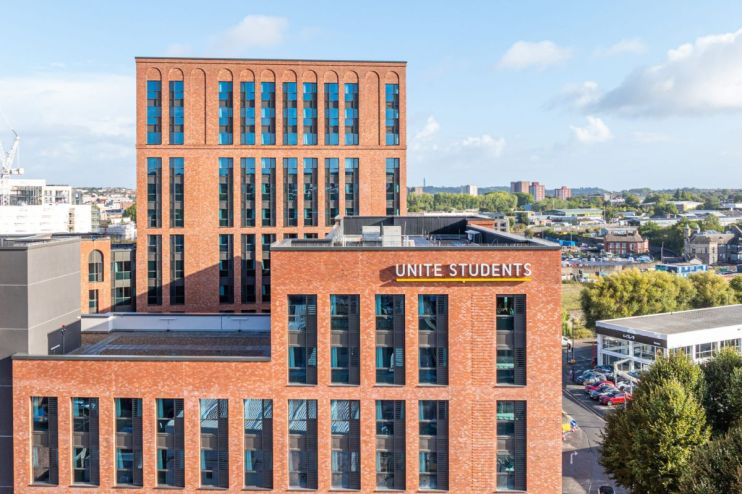 Unite Students building with brick facade and blue windows, city skyline in background under blue sky