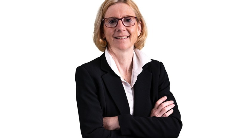 Christiane Hoffmann, a blonde woman in glasses and a black business suit, smiling with arms crossed.