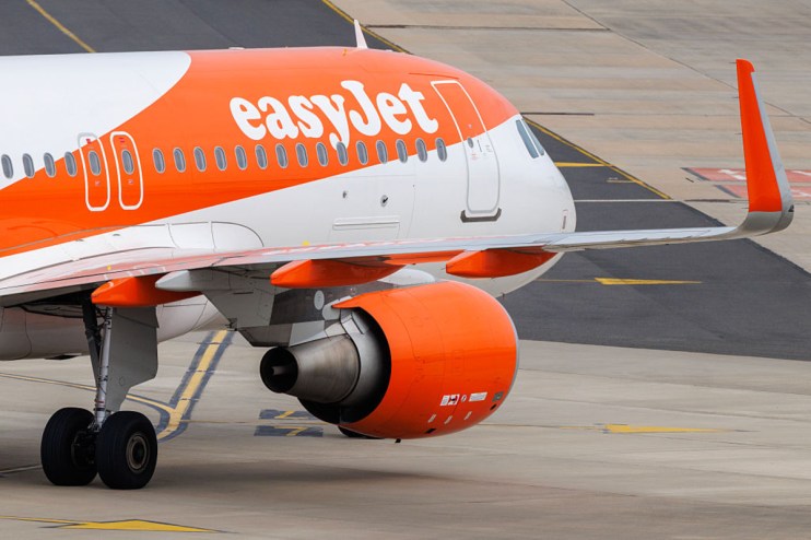 EasyJet aircraft parked at the airport terminal ready for boarding, featuring distinctive orange branding and clear blue sky.