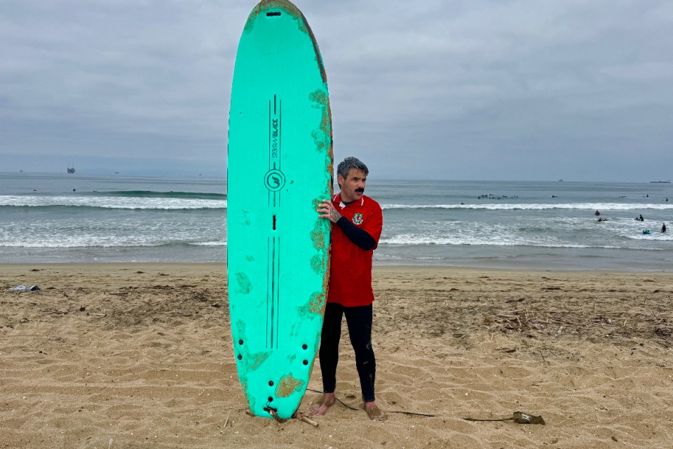 Surfer riding a wave during World Cup event at Huntington Beach, California with clear skies and spectators in the background