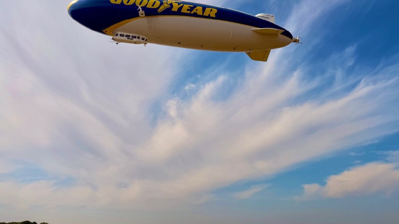Goodyear blimp hovering prominently in the sky against a clear backdrop, capturing attention with its iconic branding.