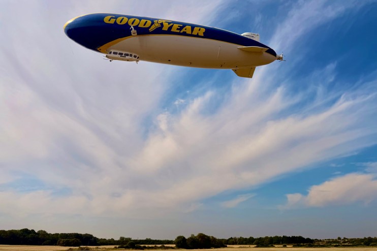 Goodyear blimp hovering prominently in the sky against a clear backdrop, capturing attention with its iconic branding.
