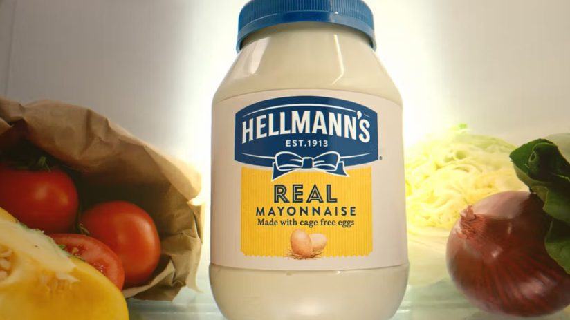 Hellmanns Real Mayonnaise jar in a refrigerator with fresh vegetables like tomatoes, lettuce, and onions