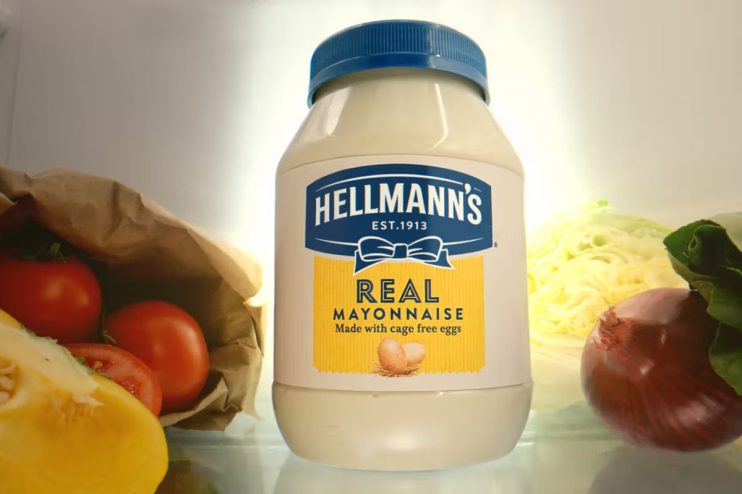 Hellmanns Real Mayonnaise jar in a refrigerator with fresh vegetables like tomatoes, lettuce, and onions