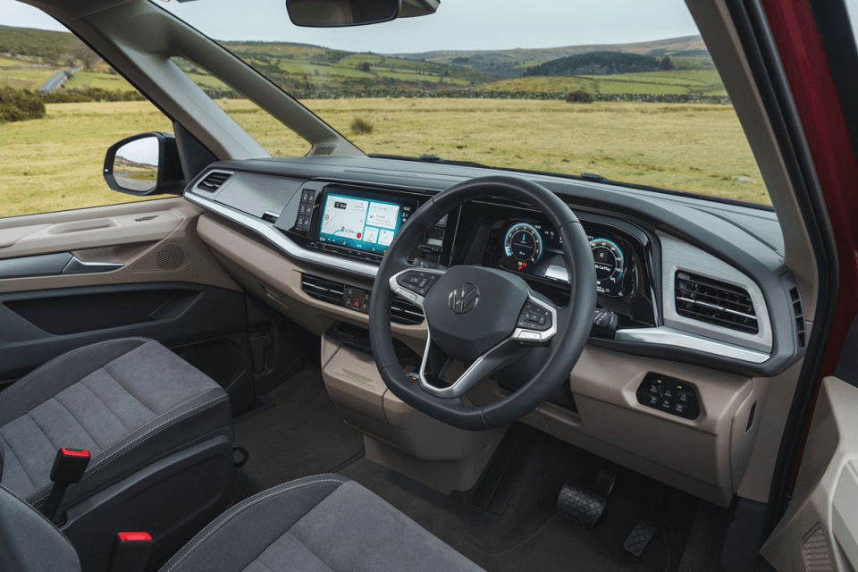 Modern car interior with digital dashboard, touchscreen navigation, and steering wheel, overlooking a scenic landscape