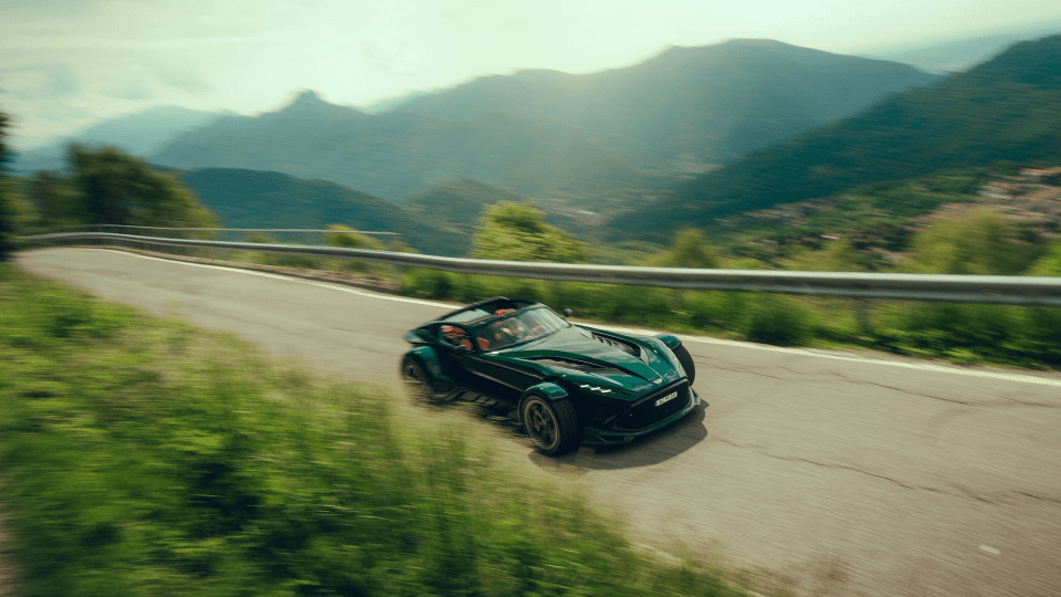 Green sports car speeding on a winding mountain road with blurred background