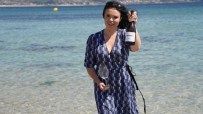Libby Albarino holding a bottle of Zarate wine and a glass by the ocean