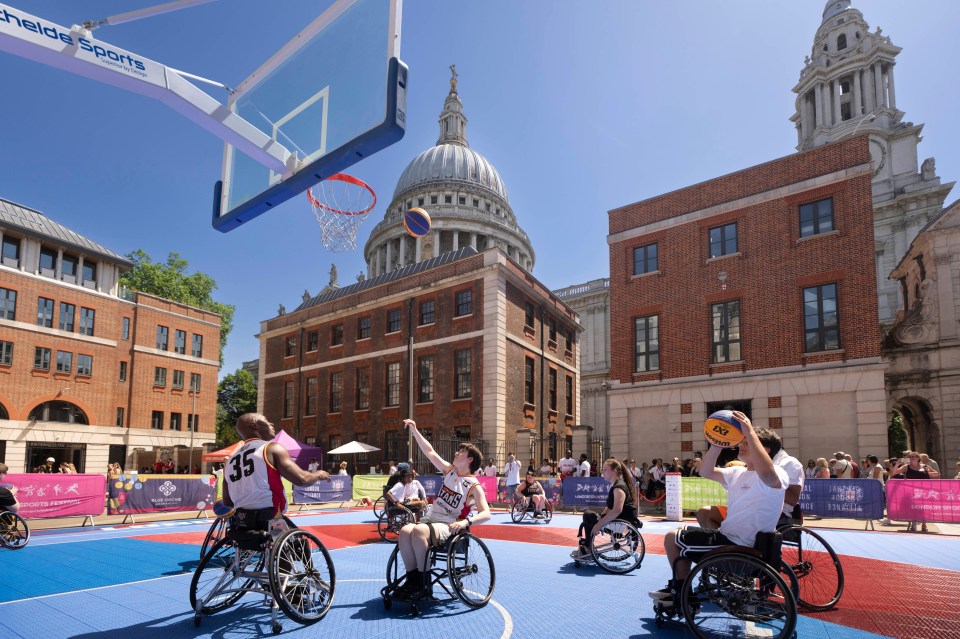 Wheelchair basketball players on a blue court during London Sports Festival community sessions, St. Pauls Cathedral in bac...