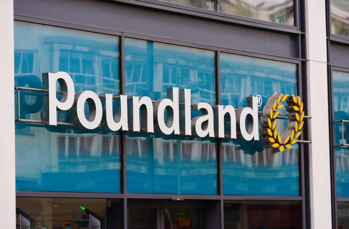 Poundland store sign with white letters and a yellow wreath logo, reflected in blue tinted windows
