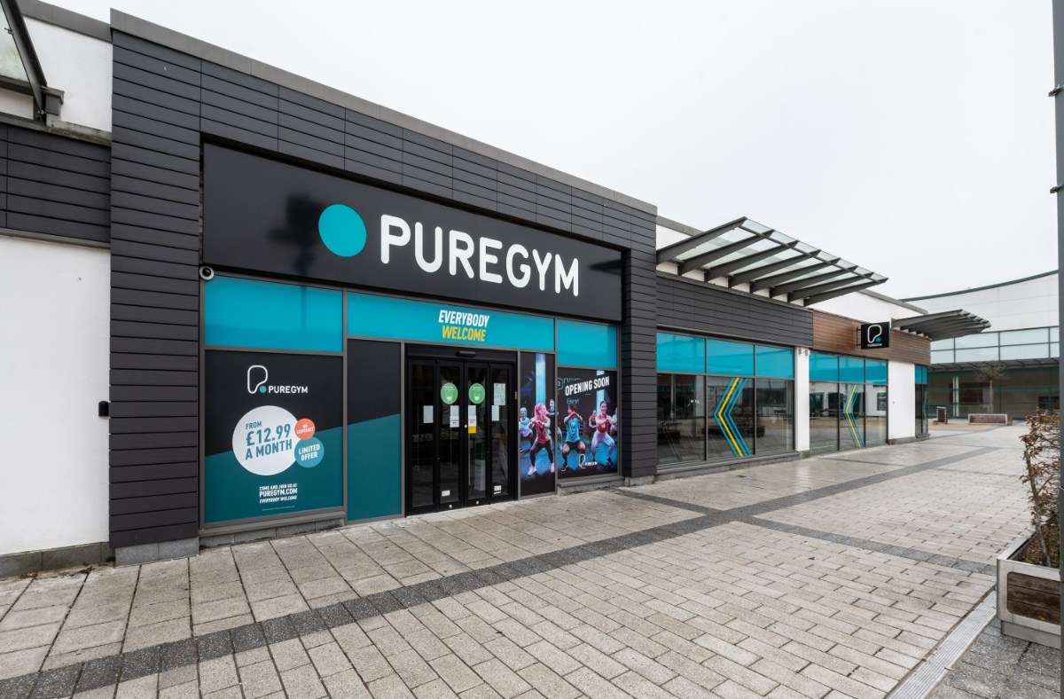 Exterior view of PureGym Aldershot, a modern fitness center with large windows and promotional signage