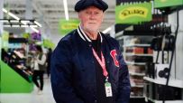Allan Leighton, former Asda CEO, in a navy jacket and cap inside an Asda store.