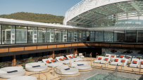 Luxury cruise ship Explora pool deck with lounge chairs and circular daybeds under a retractable glass roof