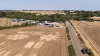 Aerial view of dry, brown farm fields affected by high temperatures, with a road and farm buildings.