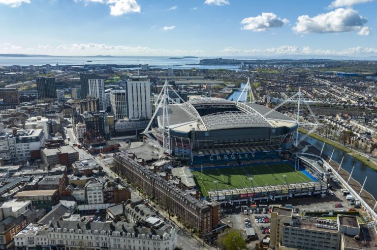 Aerial view of Cardiff city, Principality Stadium, and surrounding buildings under a blue sky