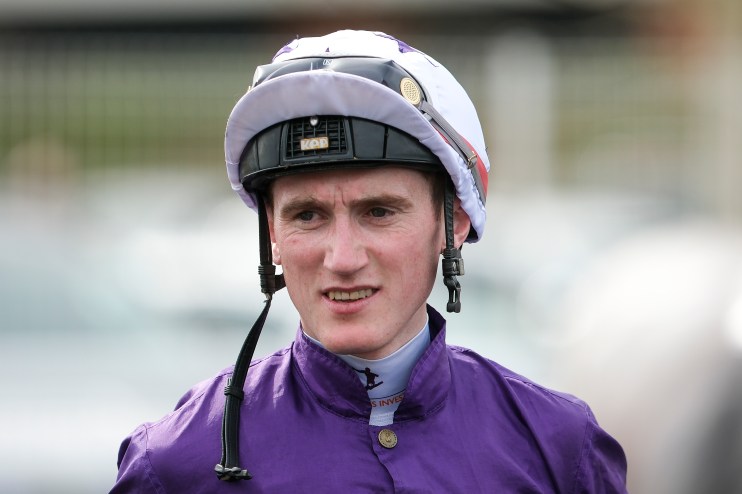 Jockey Jack Kennedy in purple silks and white helmet with KEP Italia branding, looking forward at a racecourse.