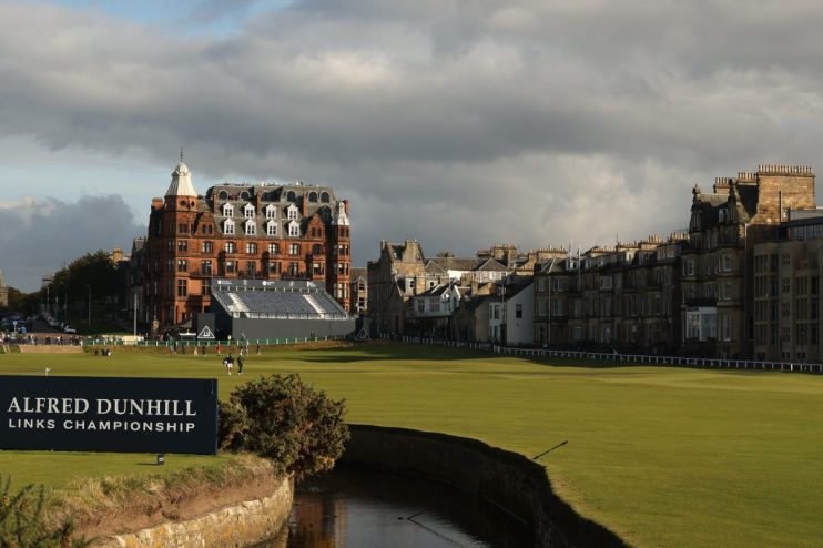 Golf course with the Old Course Hotel and town buildings in St Andrews, Scotland, under cloudy skies.