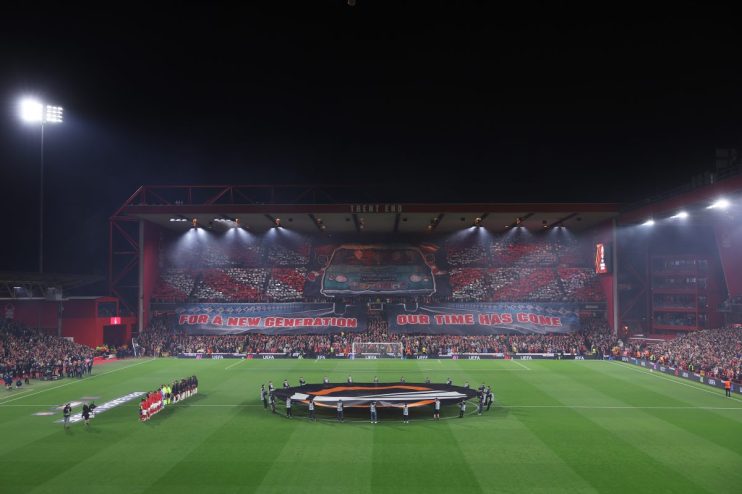 Football stadium at night with players on the pitch and a large banner reading FOR A NEW GENERATION OUR TIME HAS COME