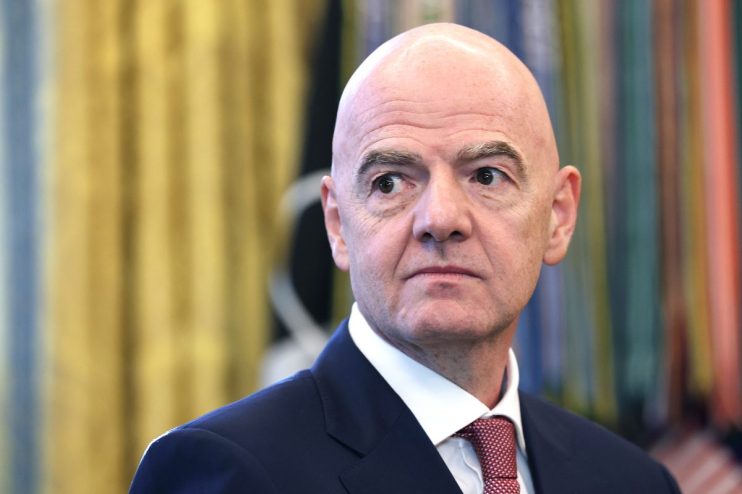 Gianni Infantino, FIFA President, in a dark suit and red tie, looking right with a serious expression.