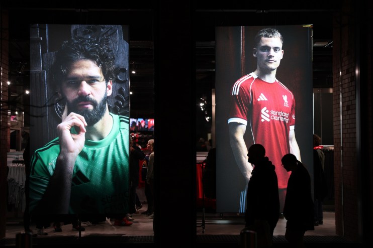 Large display screens featuring Liverpool FC players Alisson Becker and Harvey Elliott in a retail store window.