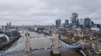 Aerial view of Tower Bridge, Thames River, and London skyline with skyscrapers on a cloudy day