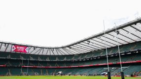 Rugby stadium interior with large screen displaying Red Roses v Ireland, goalposts, and empty green seats
