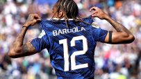 Bradley Barcola in a blue football jersey with BARCOLA 12 on the back, celebrating on the field.