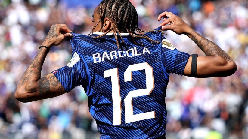 Bradley Barcola in a blue football jersey with BARCOLA 12 on the back, celebrating on the field.