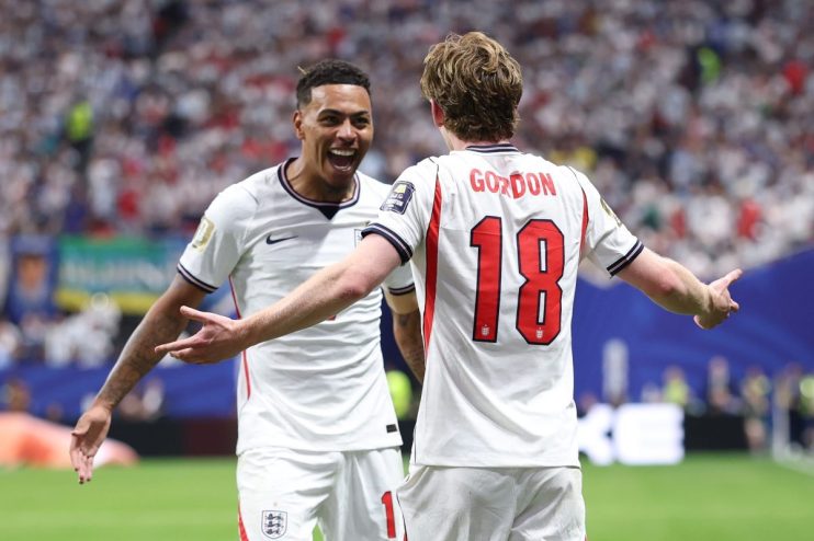 Two jubilant soccer players in white England jerseys celebrate a goal on the field.