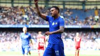 A Chelsea FC footballer in a blue kit with number 17, arm raised in celebration on the field.