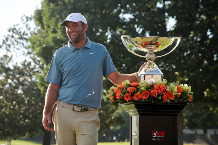 Scottie Scheffler, PGA Tour golfer, smiling next to the Tour Championship trophy with orange roses.