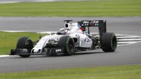 White Martini Racing Formula 1 car on a grey track with green grass borders, in motion during a race.
