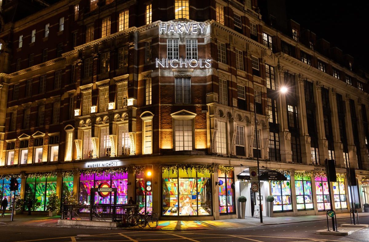 Harvey Nichols department store at night, illuminated with neon signs and colorful window displays.
