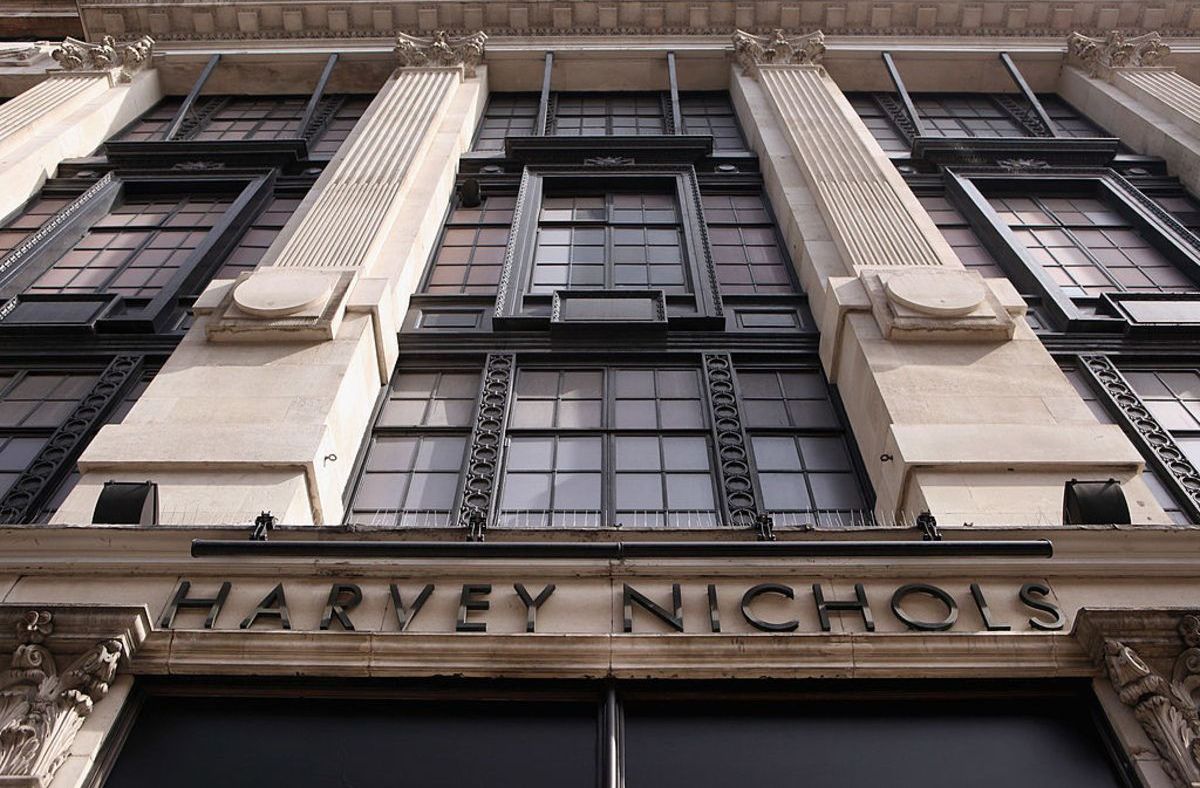 Low-angle view of the Harvey Nichols store facade with large windows, ornate columns, and prominent signage.