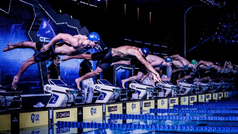 Swimmers diving from starting blocks into a pool during an ISL match at London Aquatics Centre, Nov 2019.
