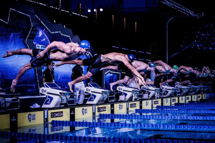 Swimmers diving from starting blocks into a pool during an ISL match at London Aquatics Centre, Nov 2019.